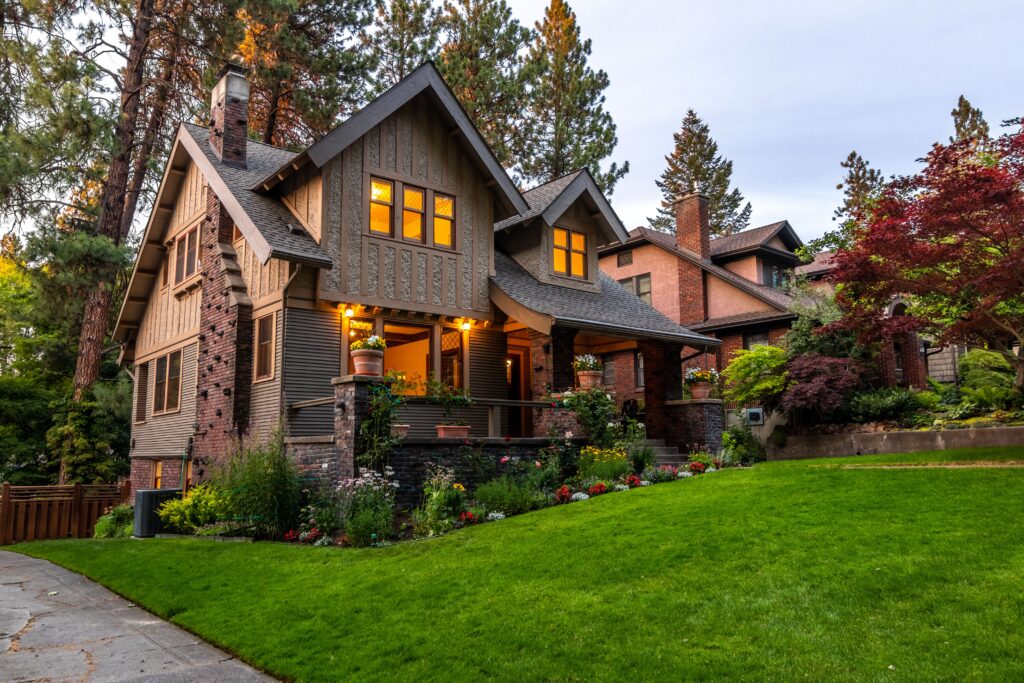 pexels photo 5524165 5524165 A beautifully lit Victorian-style house surrounded by a lush garden at twilight, showcasing classic architecture.